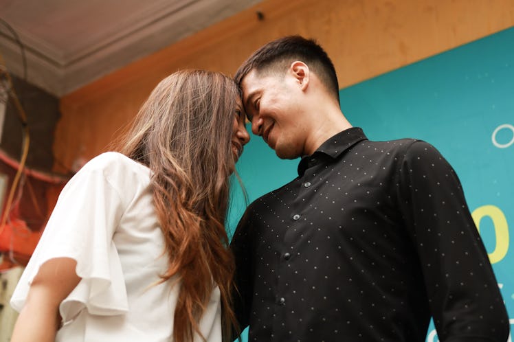 A young couple share a romantic moment in front of a colorful wall during an engagement photo shoot.
