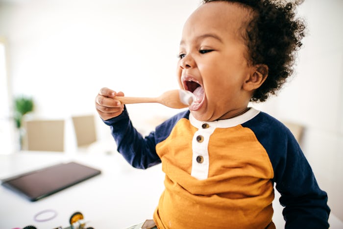 a baby boy learning to use a spoon