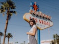 A young woman stands in front of the "Welcome To Fabulous Las Vegas" sign while on a summery trip.