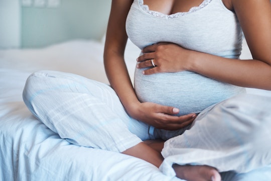 A black expecting mom sitting on a bed; new report from the Centers for Disease Control and Preventi...