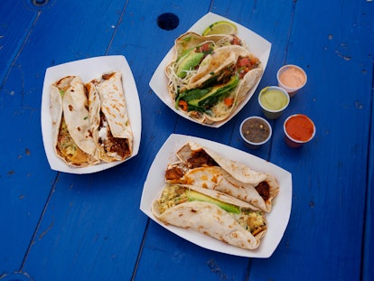 Breakfast tacos sit on a bright blue picnic table in Austin, Texas.