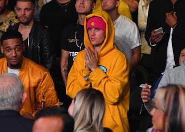 Justin Bieber is spotted in the crowd rocking a yellow hooded sweatshirt. 