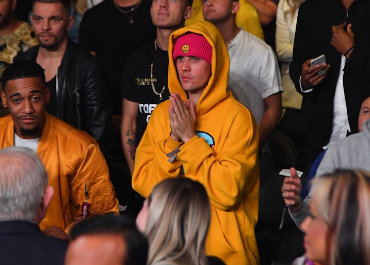 Justin Bieber is spotted in the crowd rocking a yellow hooded sweatshirt.