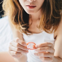 A woman contemplates a condom. If you're in a new relationship, it's OK to not use condoms according...