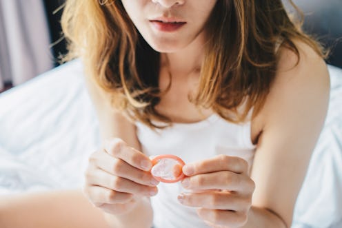 A woman contemplates a condom. If you're in a new relationship, it's OK to not use condoms according...