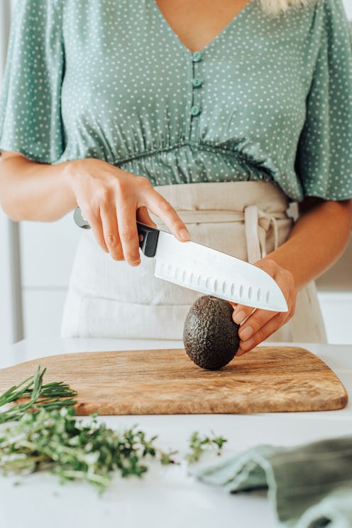 A woman slices an avocado on a wooden cutting board. Nutritionists explain foods that can balance ou...