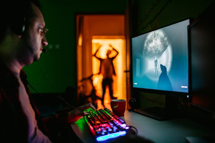 A man playing video games while someone in silhouette tries to get his attention.