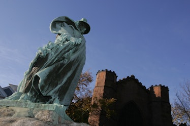 A statue outside of the Salem Witch Museum stands against a bright purple sky.