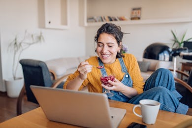 A woman eating a pomegranate with spoon during an online meeting