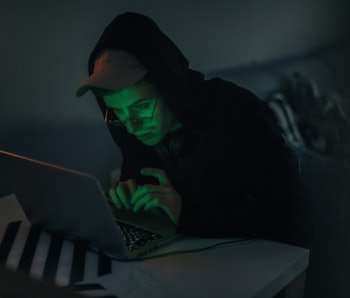 Hooded man sitting at his computer.