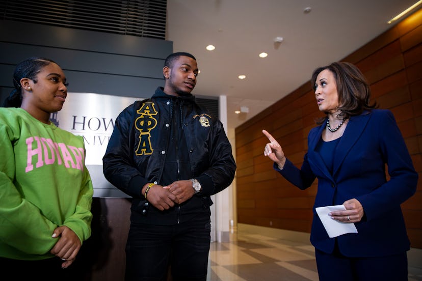 Kamala Harris in a navy suit speaking to a young man in a black jacket, and a girl in a lime hoodie