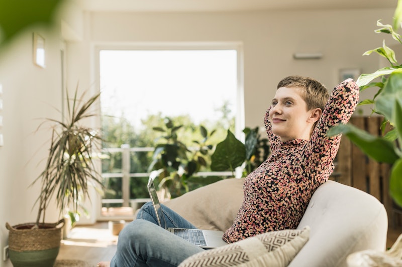 A woman with short hair sits on a white couch surrounded by plants. This article details 7 signs of high functioning ADHD in adults.