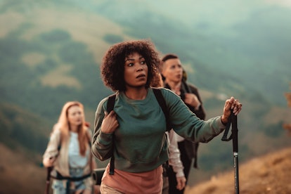 A young Black woman goes hiking with friends in the peak of fall. 