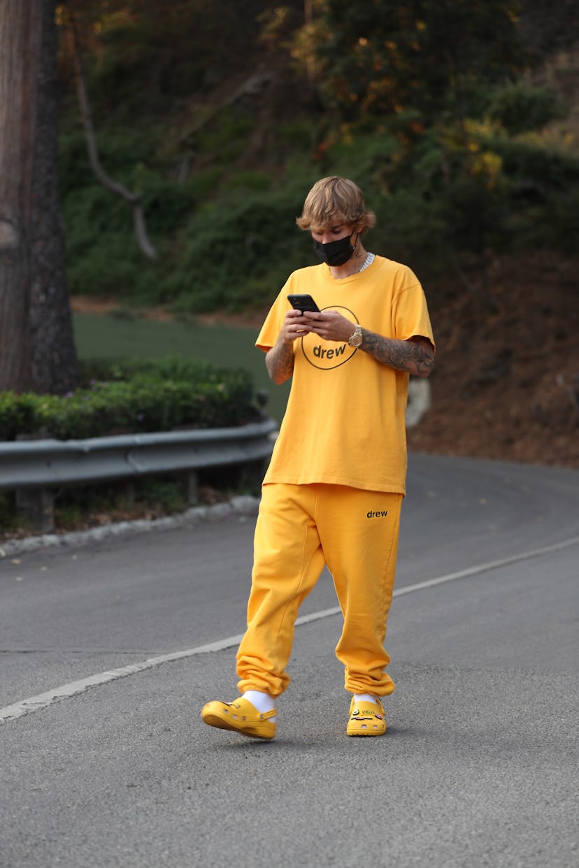 Justin Bieber walking down a road in yellow crocs followed with a yellow shirt and tracksuit 