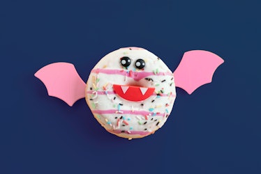 A doughnut decorated like a bat sits on a blue table. 