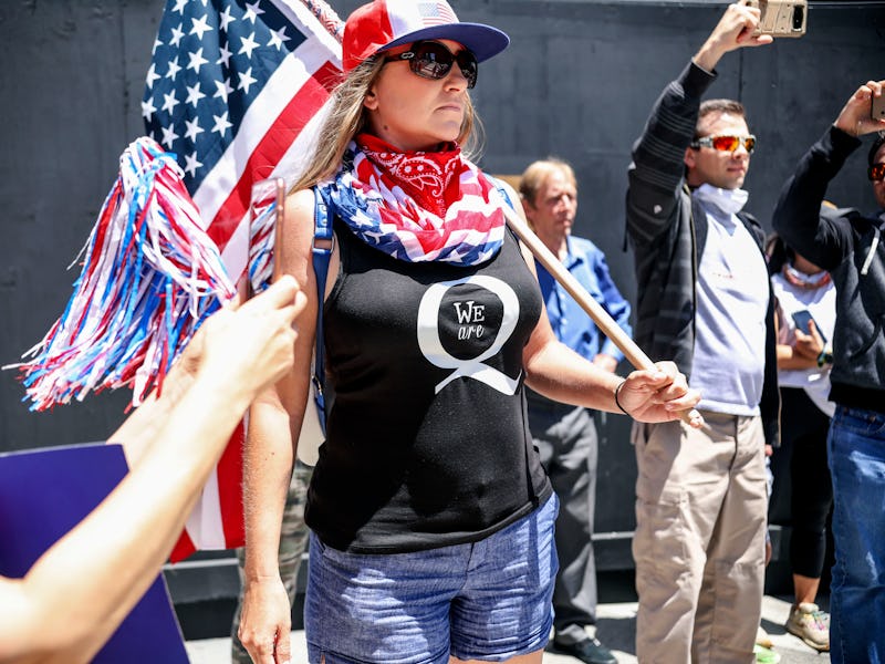 A QAnon protester in an American flag can be seen at a rally.