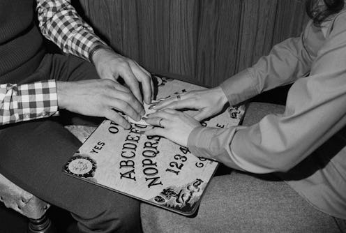 Vintage photo of people using a ouija board. The history of the ouija board demon Zozo is internet l...