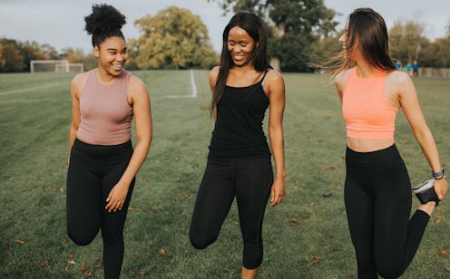 Three women stretch in a field, hoping to improve their flexibility.