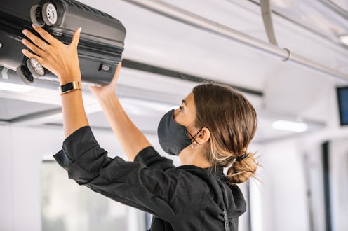 A woman puts a suitcase up on public transportation. Doctors explain how to safely travel home for t...