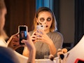 A young woman wearing Halloween makeup poses in her bathroom mirror for a selfie.