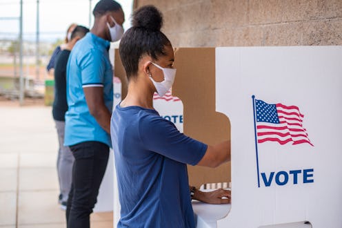 Young woman voting with a mask