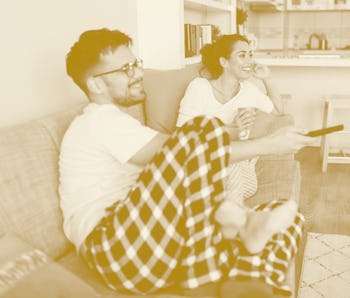 Two people watching TV on a couch.