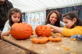 mom and girls carving jack-o-lanterns