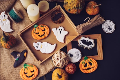 A batch of Halloween cookies, decorated like pumpkins, spiderwebs, and witch's hats, are place on th...