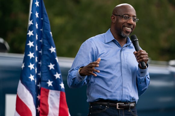 Rev. Raphael Warnock delivering a speech with the American flag behind him