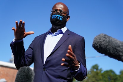 Rev. Raphael Warnock with his hands wide open, and a face mask that has "vote" written on it. 