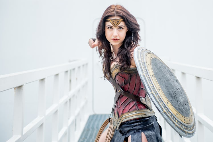 A woman dressed like Wonder Woman for Halloween lifts her fist in the air, for which she needs a sup...