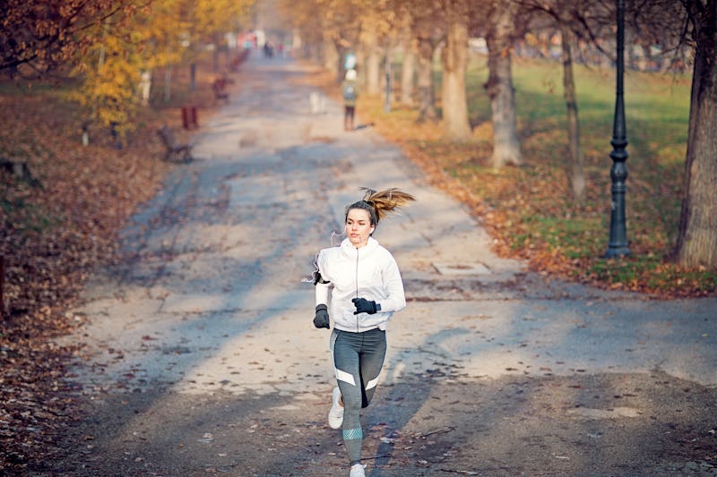 A woman runs on an autumn road listening to a political podcast.