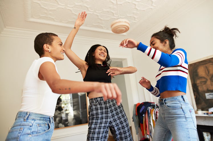 Three friends dance around in their bedroom at home. 