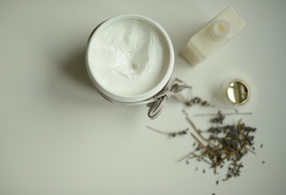 A jar of a cream with ceramides, a lotion bottle, and herbs