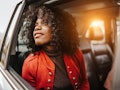 A young Black woman looks out her car window while going through a drive-thru fall experience.