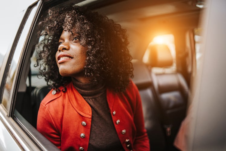 A young Black woman looks out her car window while going through a drive-thru fall experience.