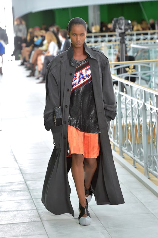 A model wearing the Louis Vuitton's Spring 2021 women's collection with a large black coat, shirt an...