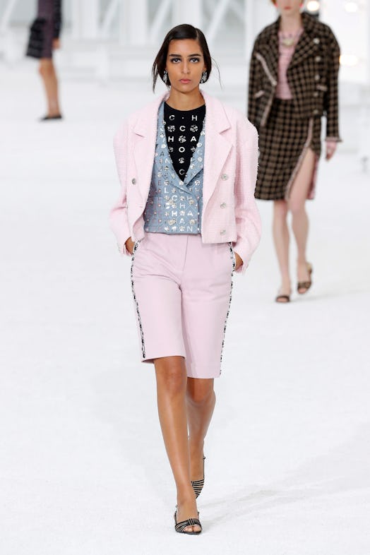 The model walks the runway in Chanel's light pink suit with short pants and a soft blue vest.