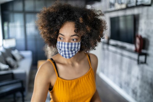 A woman with natural hair wears a blue gingham mask. Doctors debunk 8 myths about wearing face masks...