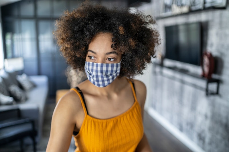 A woman with natural hair wears a blue gingham mask. Doctors debunk 8 myths about wearing face masks...