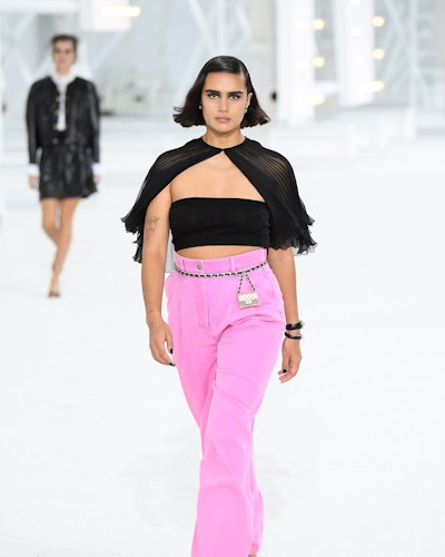 The model wears pink pair of pants with a sheer black top from Chanel's Spring 2021 Collection.