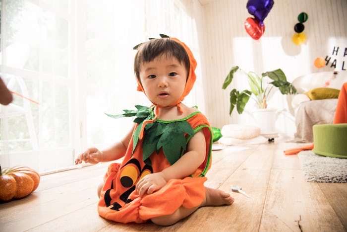 baby in pumpkin costume inside halloween