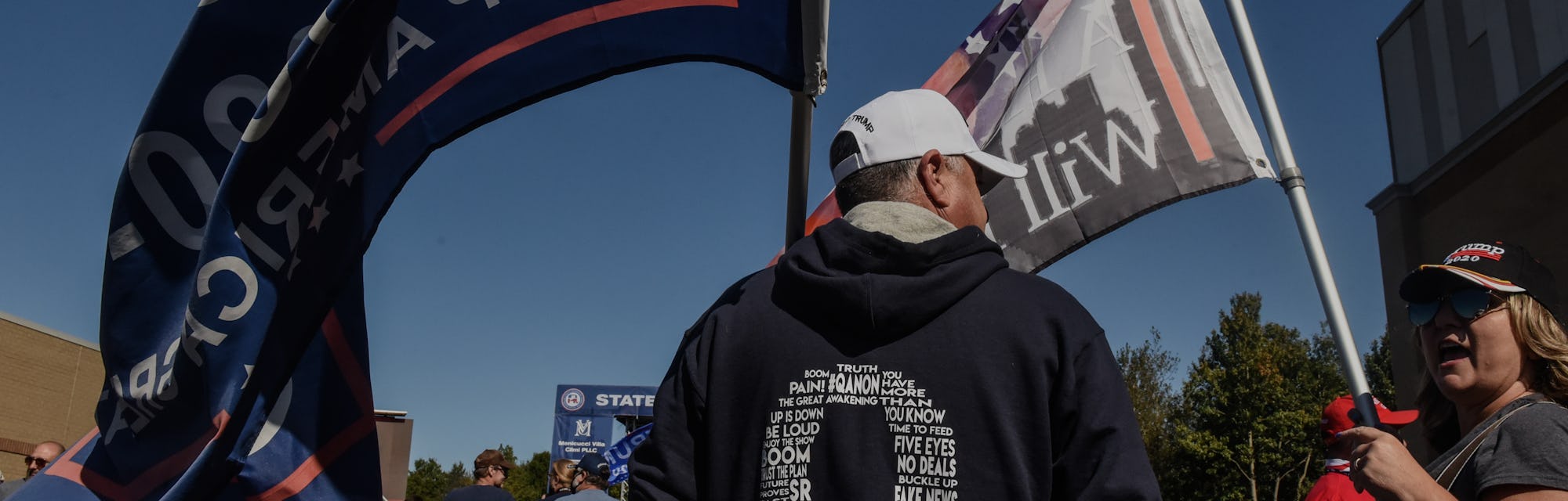 Protestors wave flags representing the QAnon conspiracy movement.