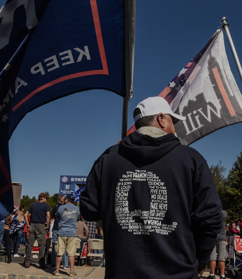 Protestors wave flags representing the QAnon conspiracy movement.