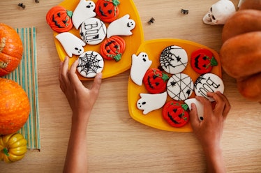 A woman's hands places Halloween cookies on a plate. 