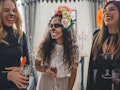 Three sorority sisters laugh while enjoying drinks and dressed up for Halloween.