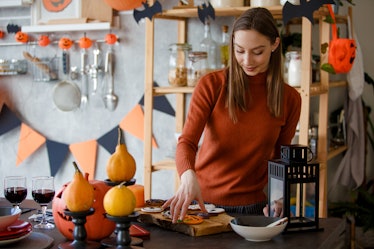 A woman arranges Halloween cookies on a board in her kitchen. 