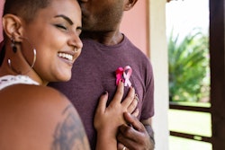 woman and man hug wearing breast cancer month awareness ribbons