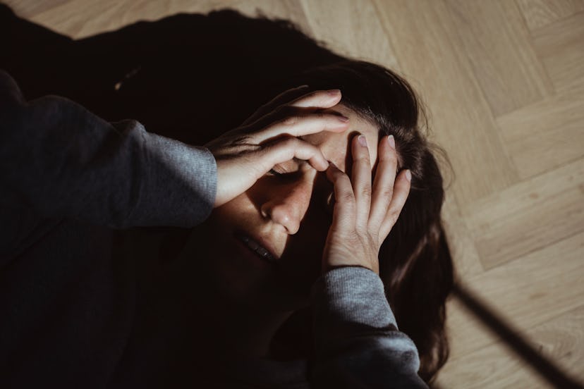 A woman lying on the floor in shadow, with a hangover that's gotten worse as the day goes on.