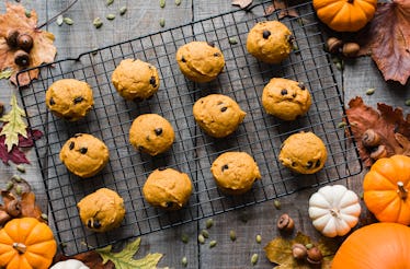 Pumpkin spice cookies with chocolate chips sit on a rack with pumpkins and fall leaves surrounding i...